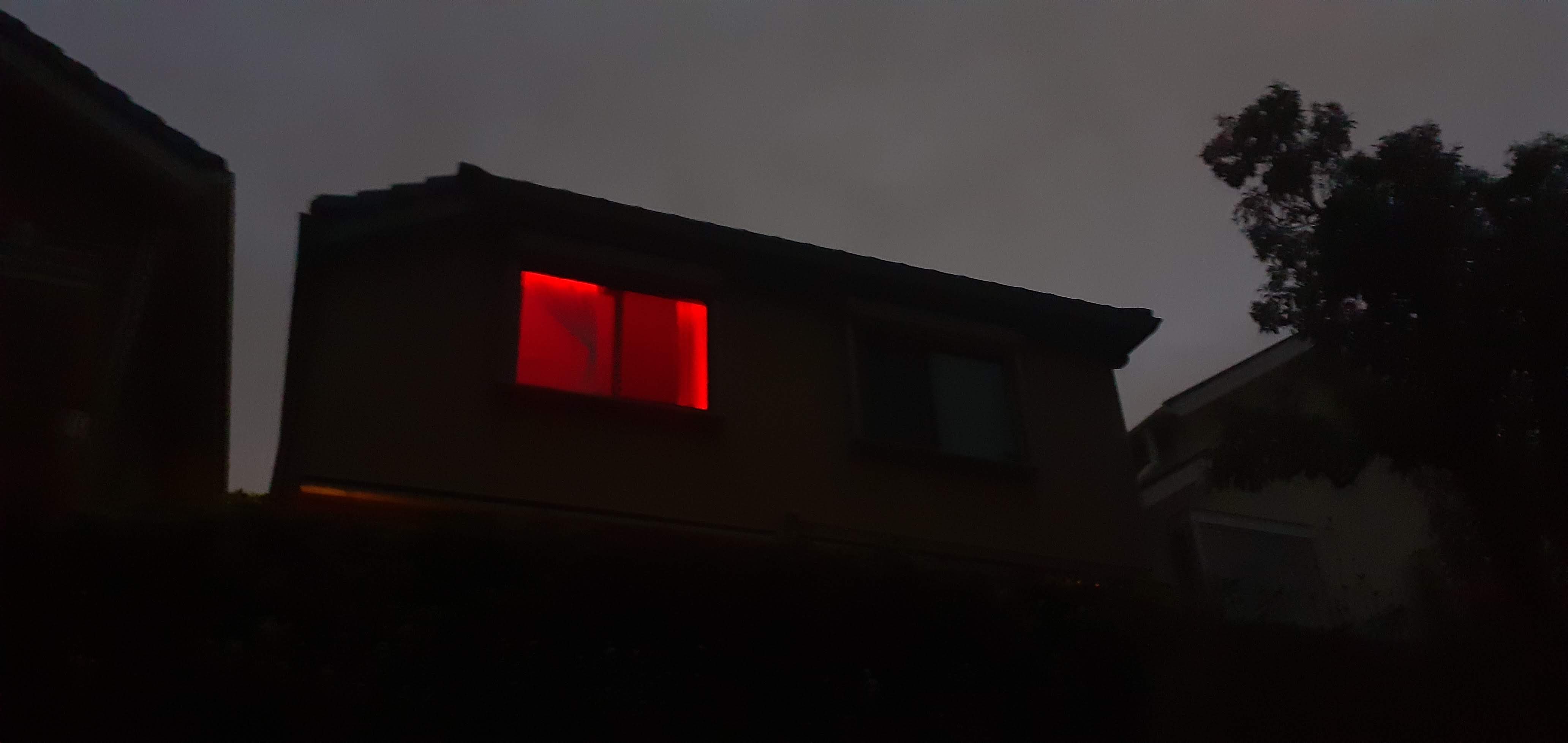 dark house with a window lit red